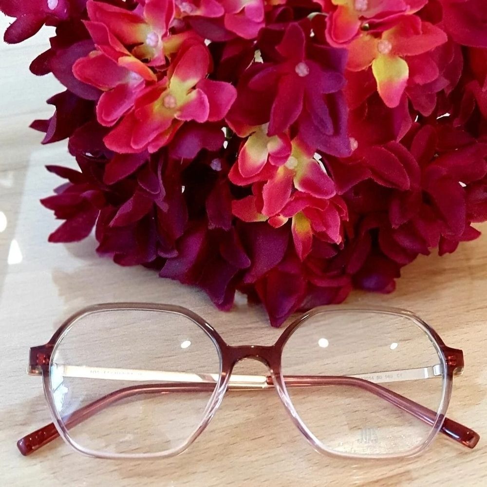 Stilvolle rosa Brille auf einem Holztisch mit Blumen
